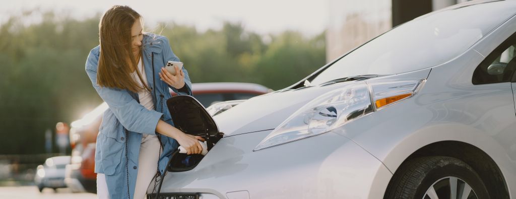 Woman charging electro car at the electric gas station