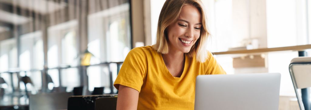 Photo of joyful nice woman using laptop and smiling while sitting with laptop