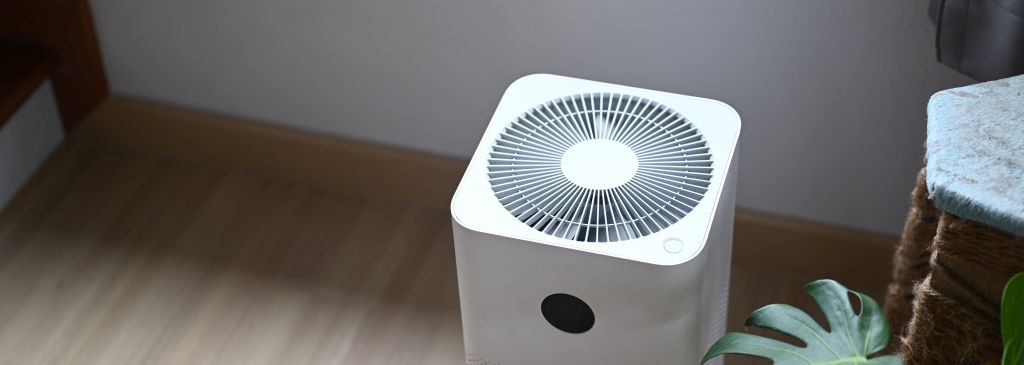 Air purifier in comfortable living room with house plant on the wooden floor.