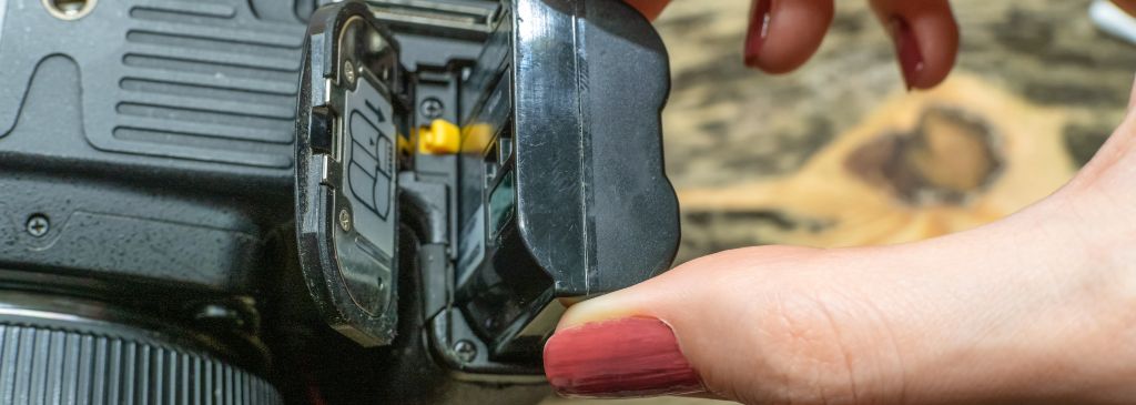 A photographer changes the battery in his SLR camera while shooting in the Studio. focus on the camera battery